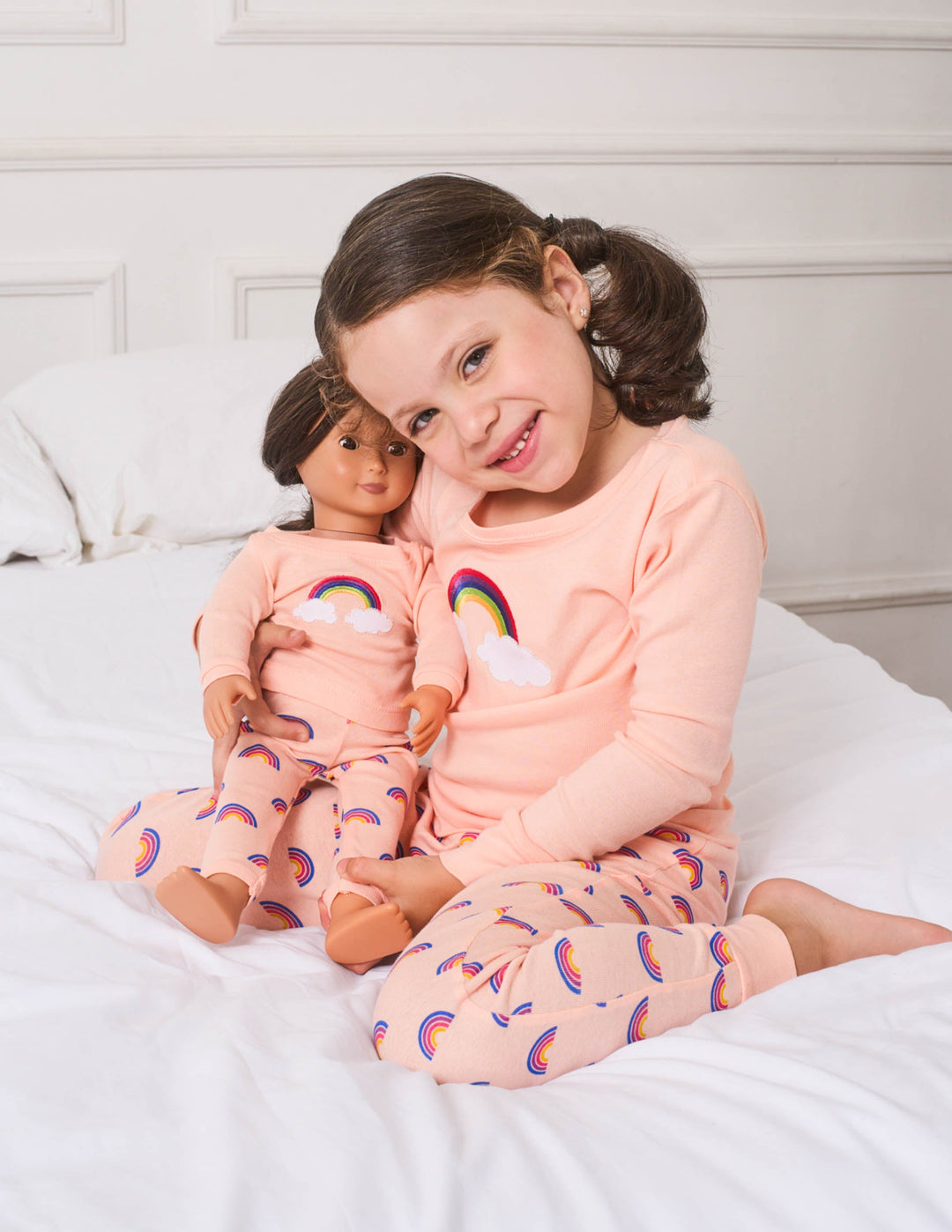girl and doll in pink rainbow pajamas 
