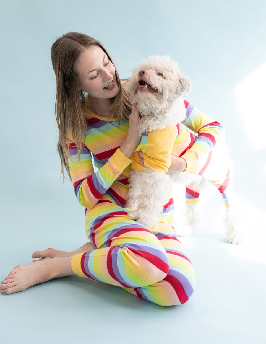 A woman in a Leveret cotton pajamas playing with her dog, demonstrating the pajama's versatility